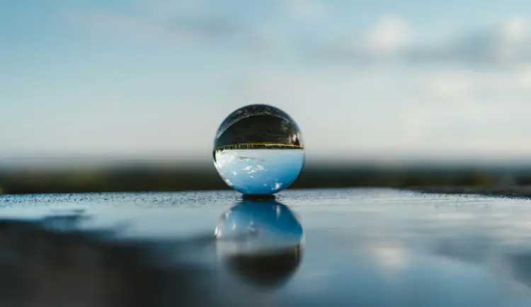 Une sphère de verre sur une surface réfléchissante.